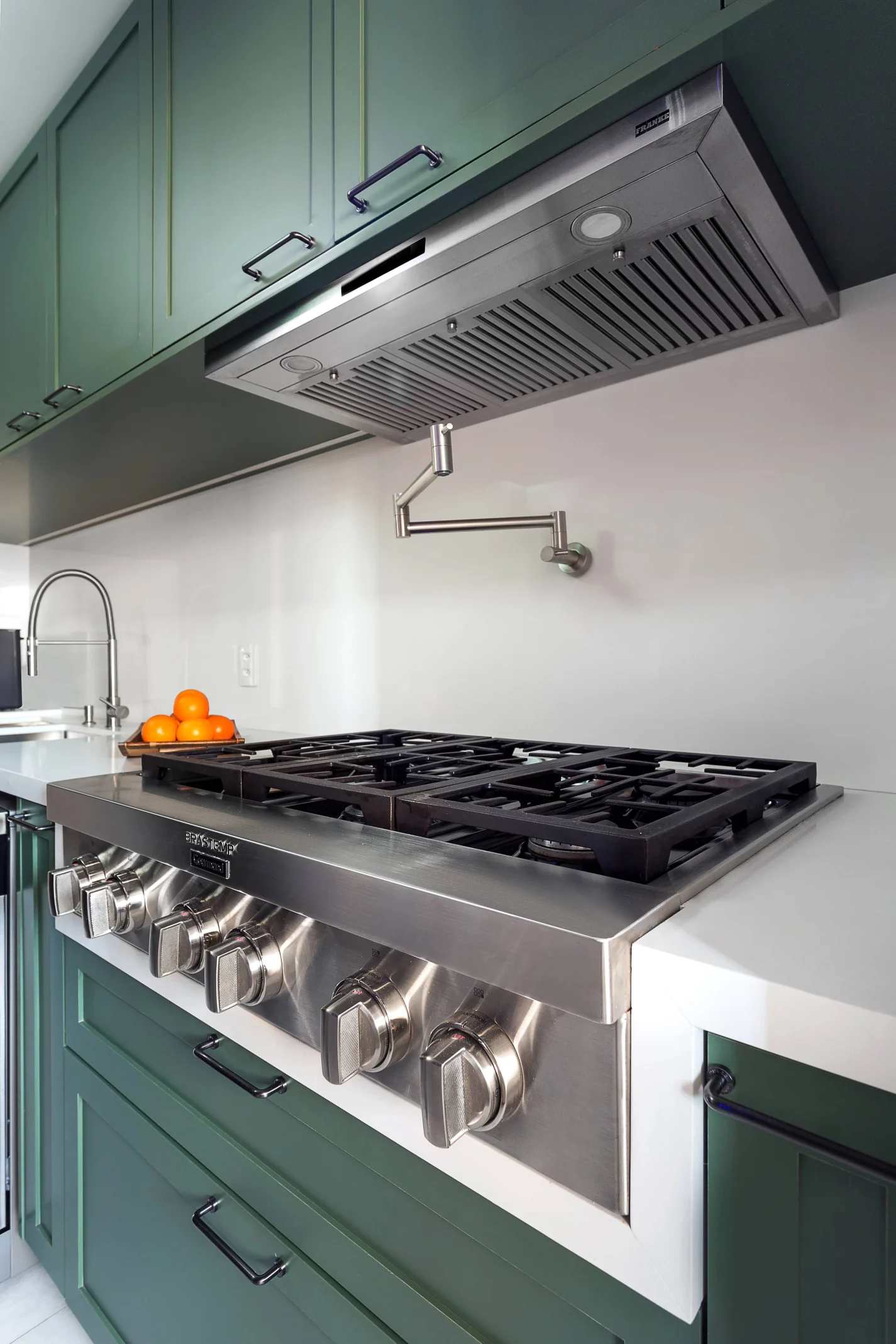 Torneira, monocomando e pot filler: arquiteta explica como fazer a melhor escolha para cozinhas e lavanderias. Projeto de Juliana Faria. Na foto, cozinha moderna com fogão de seis bocas e uma torneira articulada de parede acima do cooktop.